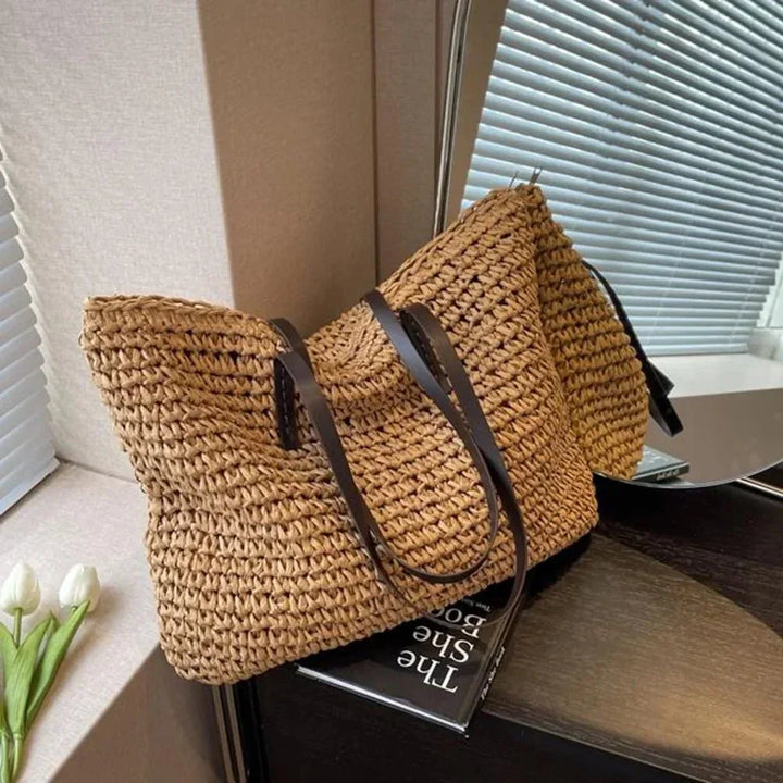 Large woven straw tote bag held by hand